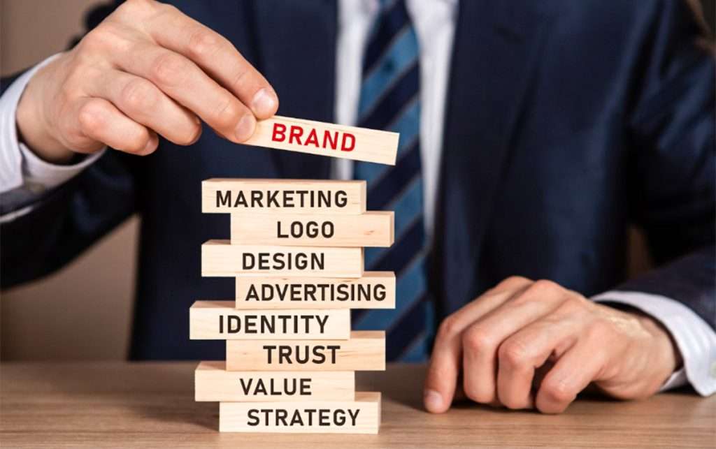 Businessman stacking wooden blocks labeled with branding elements like marketing, logo, design, and trust, emphasizing the importance of visual identity—Why Quality Graphic Design Matters for Your Business?